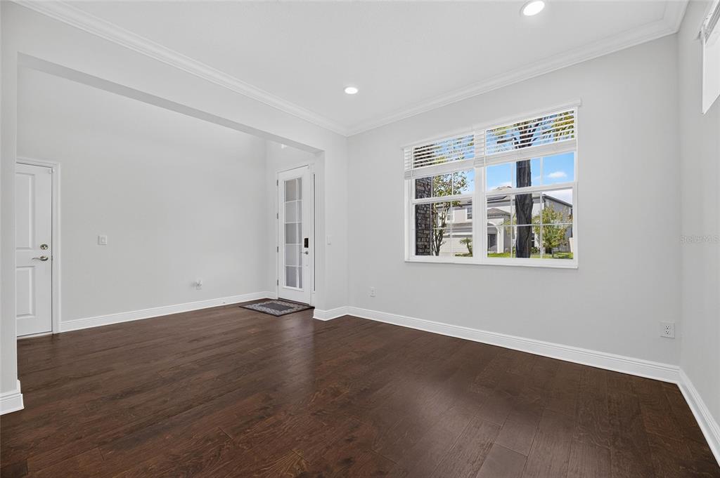An empty room with dark hardwood floors, light gray walls, and a glass-paneled entry door — 10845 SUNDRIFT DRIVE, TAMPA, FL