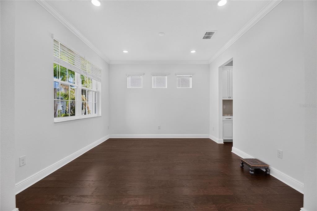 An empty dining room features dark hardwood floors, white walls, recessed lighting, and large windows — 10845 SUNDRIFT DRIVE, TAMPA, FL