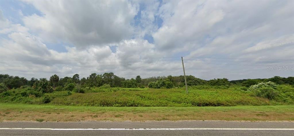 A view of a vacant, grassy lot with trees and a utility pole under a sky — US-27, FROSTPROOF, FL