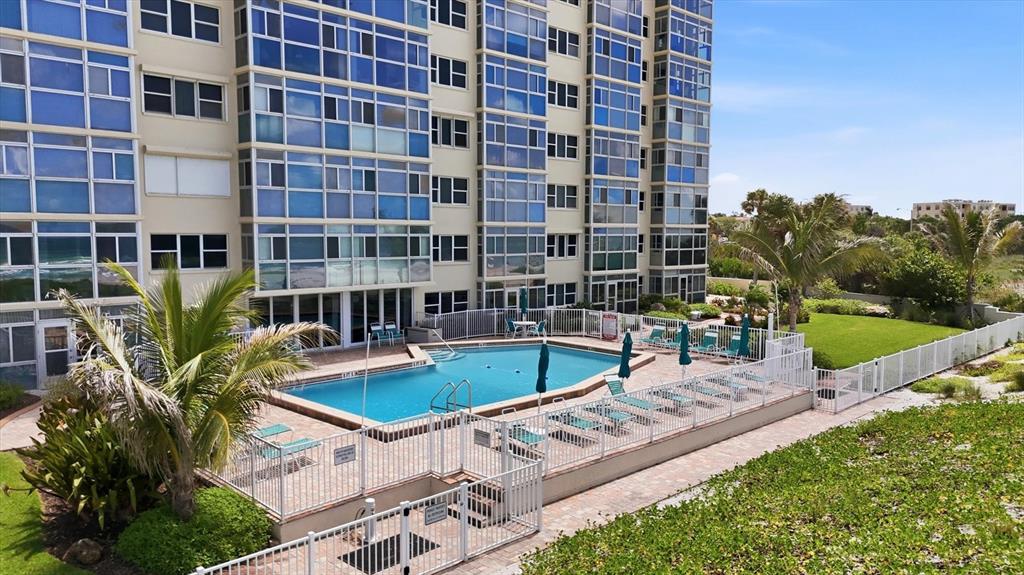 An outdoor swimming pool sits on a patio next to a multi-story residential building — 255 THE ESPLANADE N UNIT 707, VENICE, FL