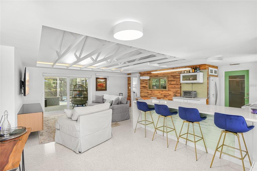 An open-concept living area features a kitchen island with blue stools and a vaulted ceiling — 2560 SUNNYSIDE STREET, SARASOTA, FL