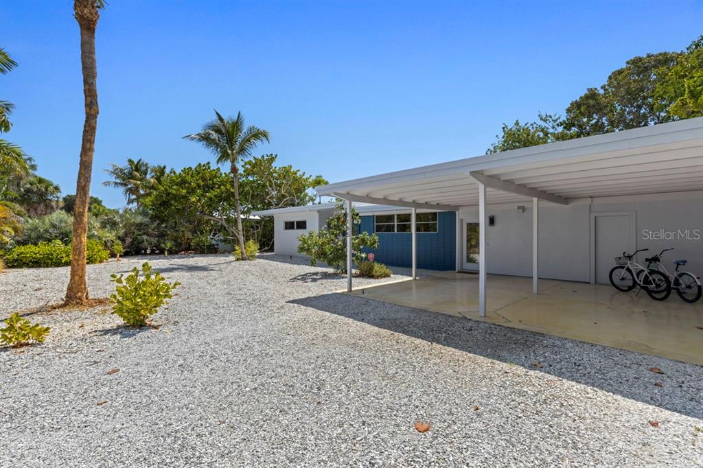 A single-story house features a gravel yard, a white carport, and blue exterior siding — 1165 MORNINGSIDE PLACE, SARASOTA, FL