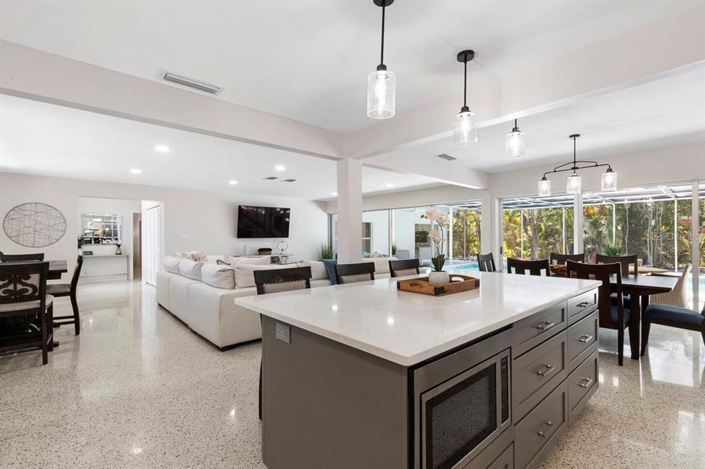 A modern kitchen island with a microwave faces a living room and dining area — 1165 MORNINGSIDE PLACE, SARASOTA, FL