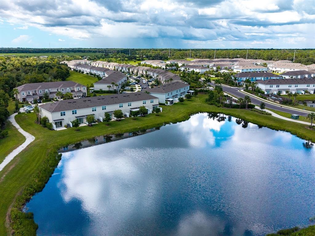 An aerial view of a multi-unit townhouse building situated next to a large pond — 8632 LUNAR SKYE STREET, SARASOTA, FL