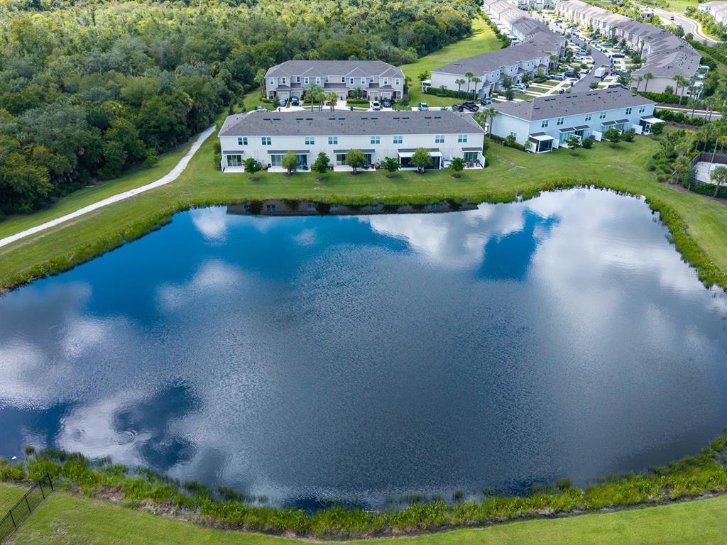 An aerial view of a residential community featuring townhomes surrounding a large retention pond — 8632 LUNAR SKYE STREET, SARASOTA, FL