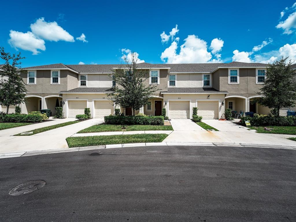 An aerial view shows townhouses situated behind a large pond surrounded by green space — 8632 LUNAR SKYE STREET, SARASOTA, FL