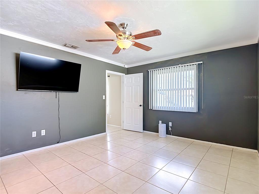 A room with tiled floors, a ceiling fan, a wall-mounted television, and a window — 1832 VAN LOON TERRACE, CAPE CORAL, FL
