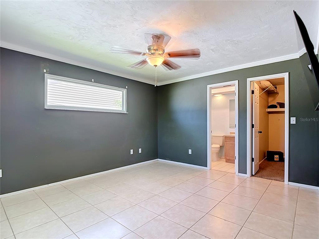 A bedroom with dark gray walls, tile flooring, a ceiling fan, and an attached bathroom — 1832 VAN LOON TERRACE, CAPE CORAL, FL