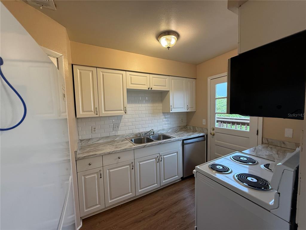 A kitchen features white cabinets, a subway tile backsplash, marble-look countertops, and stainless steel appliances — 1920 E EDGEWOOD DRIVE UNIT N8, LAKELAND, FL