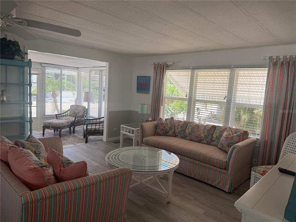 A living room features striped sofas, a glass-topped coffee table, and an adjacent sunroom — 5710 ORANGE BLOSSOM ROAD, VENICE, FL
