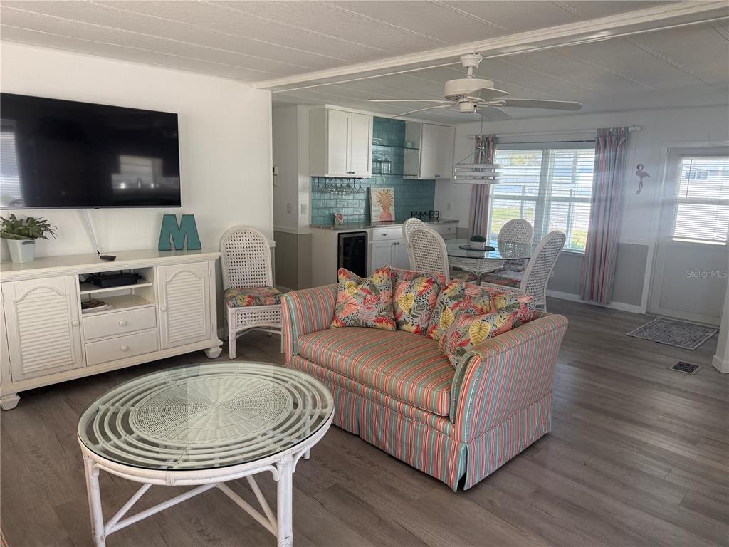 A living room and dining area feature light wood floors, a striped sofa, and cabinetry — 5710 ORANGE BLOSSOM ROAD, VENICE, FL