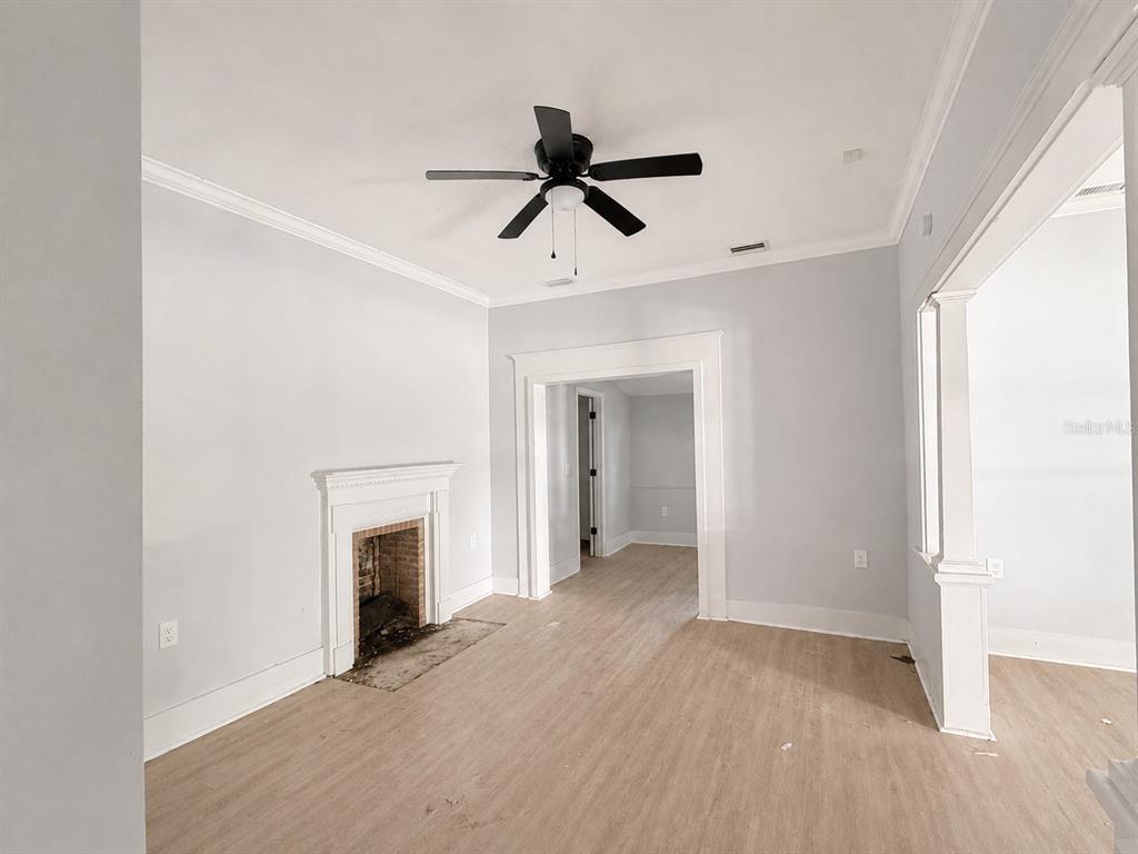 A living room features light wood flooring, a fireplace, and a black ceiling fan — 204 N MONROE AVENUE, ARCADIA, FL