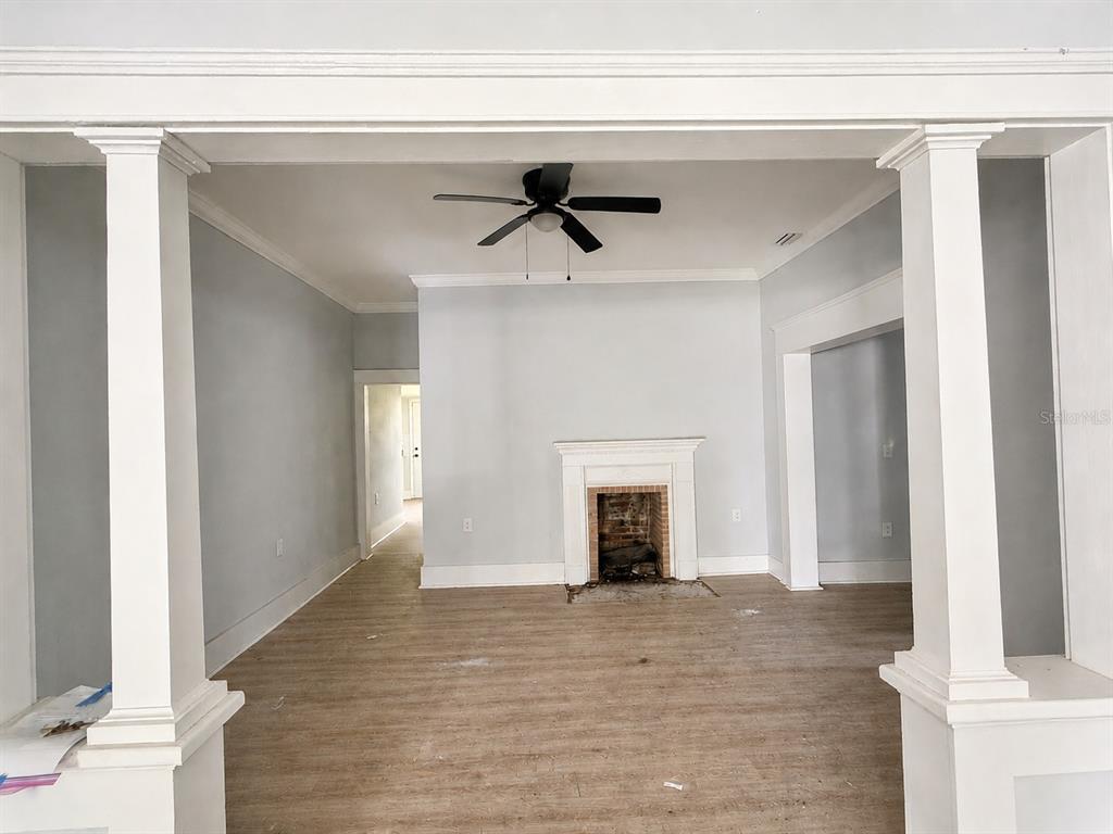 A living room features light-colored walls, wood-look flooring, a ceiling fan, and a fireplace — 204 N MONROE AVENUE, ARCADIA, FL