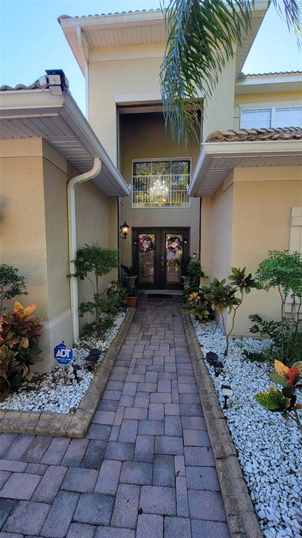 A paved walkway leads to the front entrance of a two-story house with stucco walls — 3731 EAGLE ISLE CIRCLE, KISSIMMEE, FL