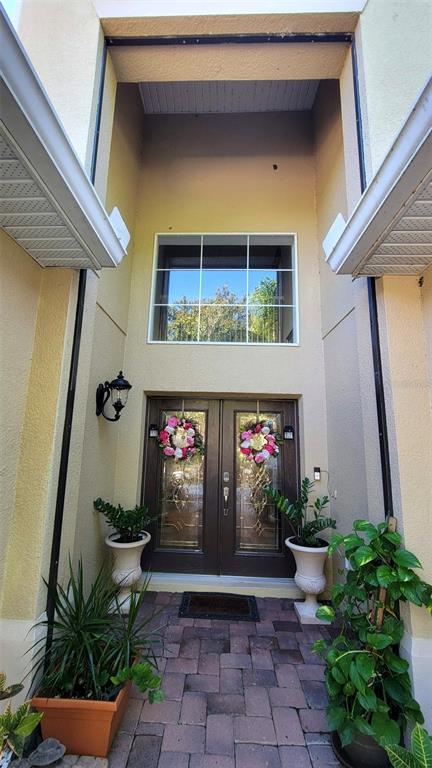 A front entryway features double glass doors, a large window, and potted plants on pavers — 3731 EAGLE ISLE CIRCLE, KISSIMMEE, FL