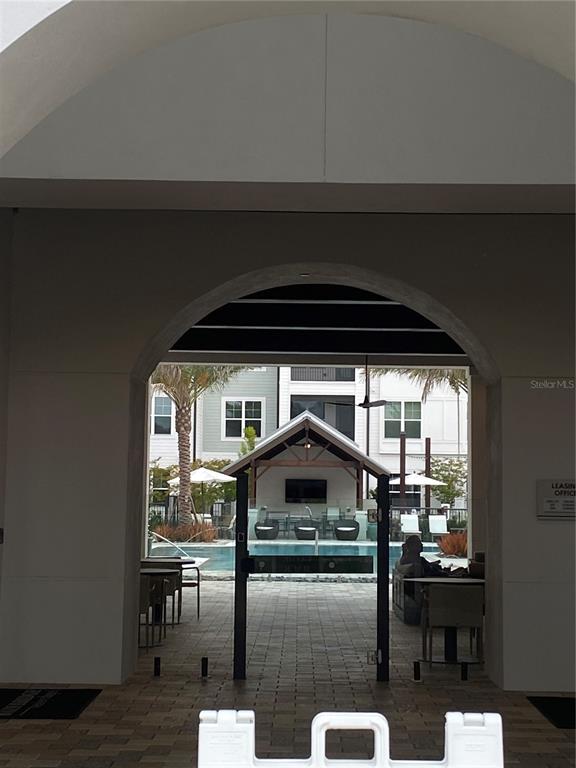 A view through an arched entryway reveals a swimming pool and a covered outdoor lounge — 32475 SUGARPLUM LOOP UNIT 4120, WESLEY CHAPEL, FL