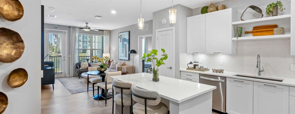 A modern kitchen with white cabinets and a quartz island opens into a living area — 32475 SUGARPLUM LOOP UNIT 4120, WESLEY CHAPEL, FL