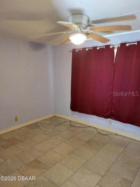 An empty room features light-colored tile flooring, lavender walls, and a ceiling fan — 324 N JANICE LANE, ORMOND BEACH, FL