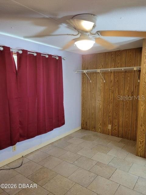 A room with tiled flooring, wood-paneled walls, a ceiling fan, and red curtains — 324 N JANICE LANE, ORMOND BEACH, FL