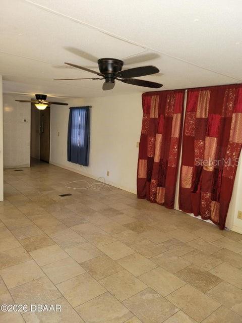 A room with tiled floors, two ceiling fans, and red patterned curtains over a window — 324 N JANICE LANE, ORMOND BEACH, FL