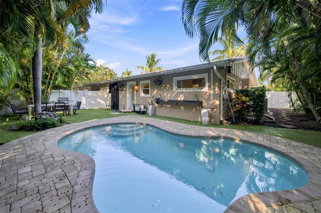 A backyard features a kidney-shaped swimming pool, a paved patio, and a single-story house exterior — 205 82ND STREET, HOLMES BEACH, FL