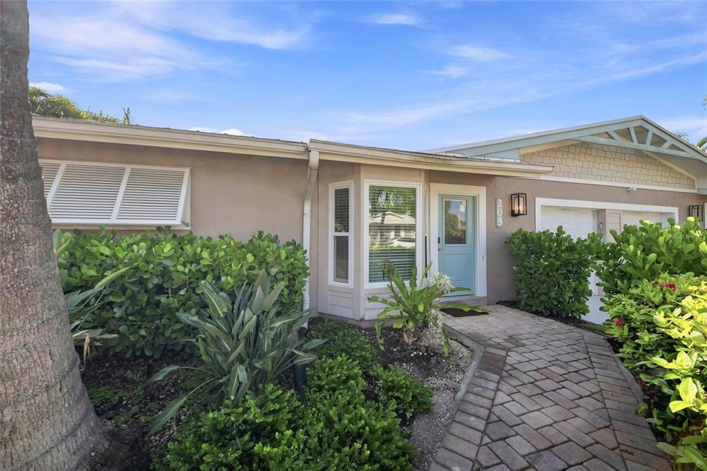 A paved walkway leads to the light blue front door of a single-story stucco home — 205 82ND STREET, HOLMES BEACH, FL