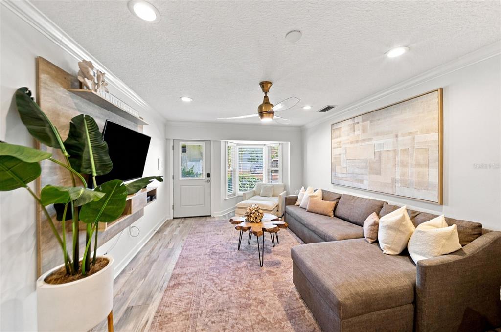 A living room features a sectional sofa, a wood-topped coffee table, and a wall-mounted television — 205 82ND STREET, HOLMES BEACH, FL