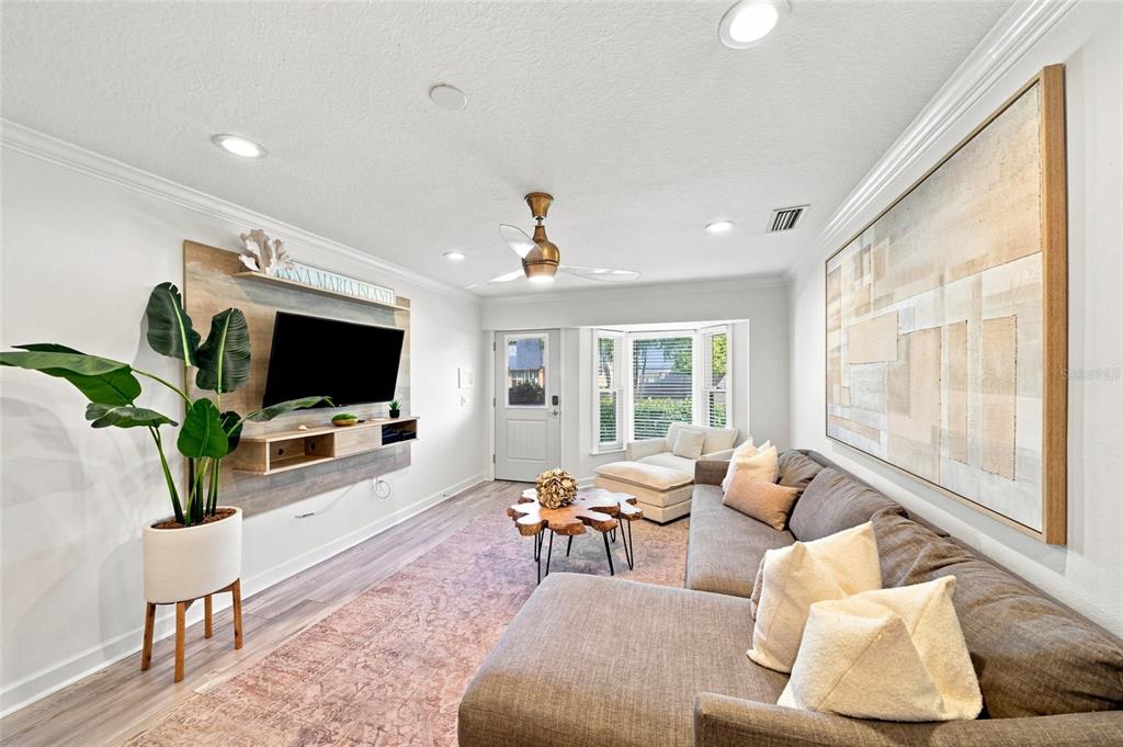 A living room features a gray sectional sofa, a wall-mounted television, and a wood-slab coffee table — 205 82ND STREET, HOLMES BEACH, FL