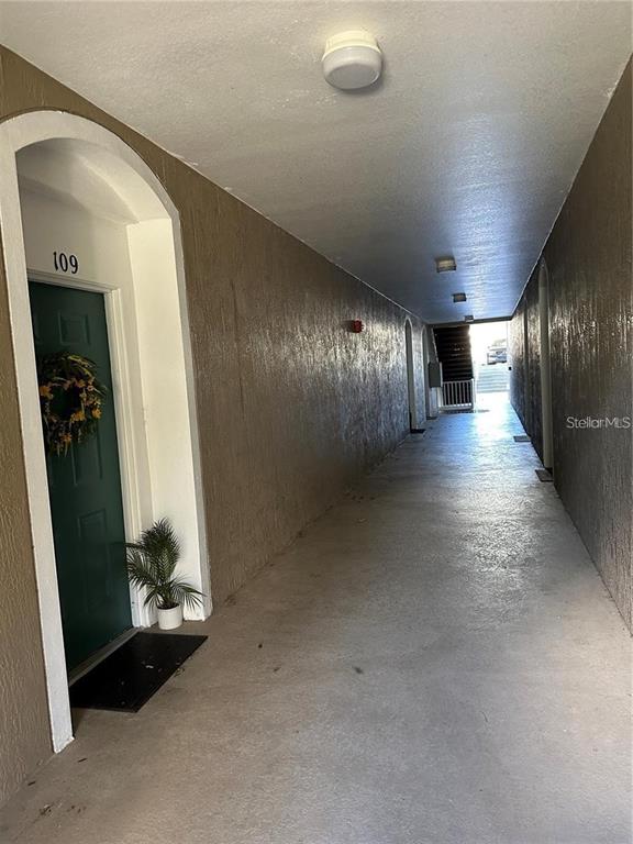 An outdoor apartment hallway features a green door labeled 109 with a wreath and plant — 588 BRANTLEY TERRACE WAY UNIT 109, ALTAMONTE SPRINGS, FL