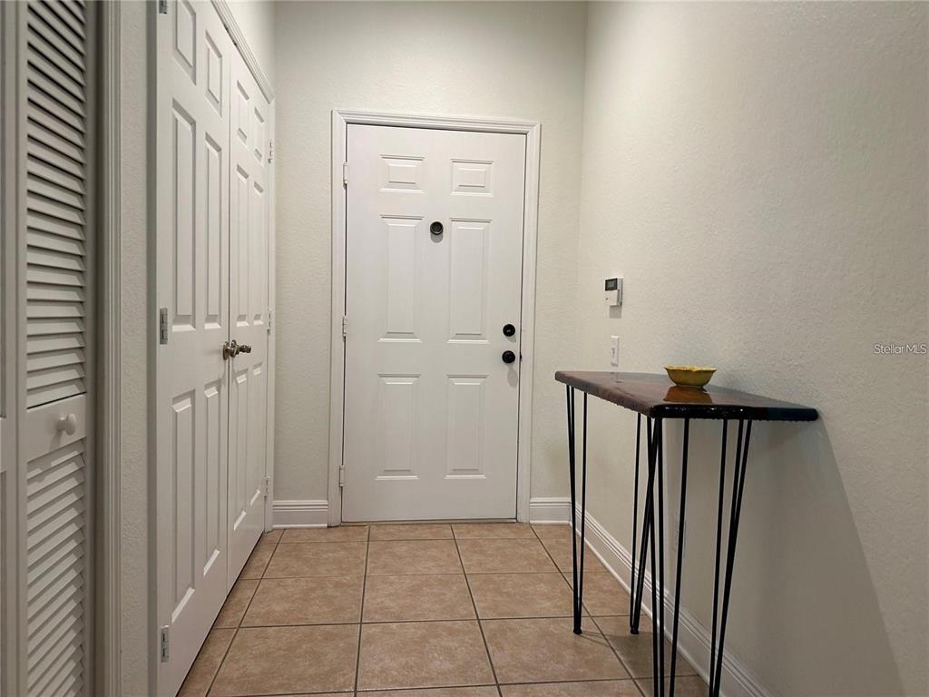 An entryway features a white front door, a closet with louvered doors, and a console table — 588 BRANTLEY TERRACE WAY UNIT 109, ALTAMONTE SPRINGS, FL