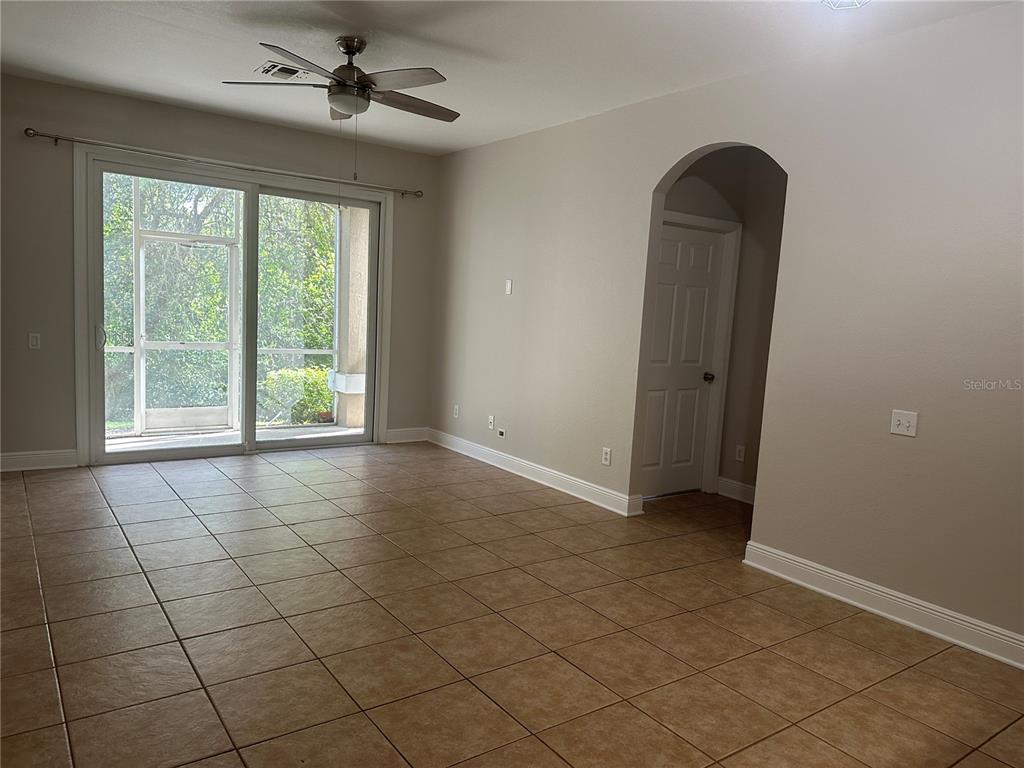 An empty room features beige tile flooring, a ceiling fan, and a sliding glass door — 588 BRANTLEY TERRACE WAY UNIT 109, ALTAMONTE SPRINGS, FL