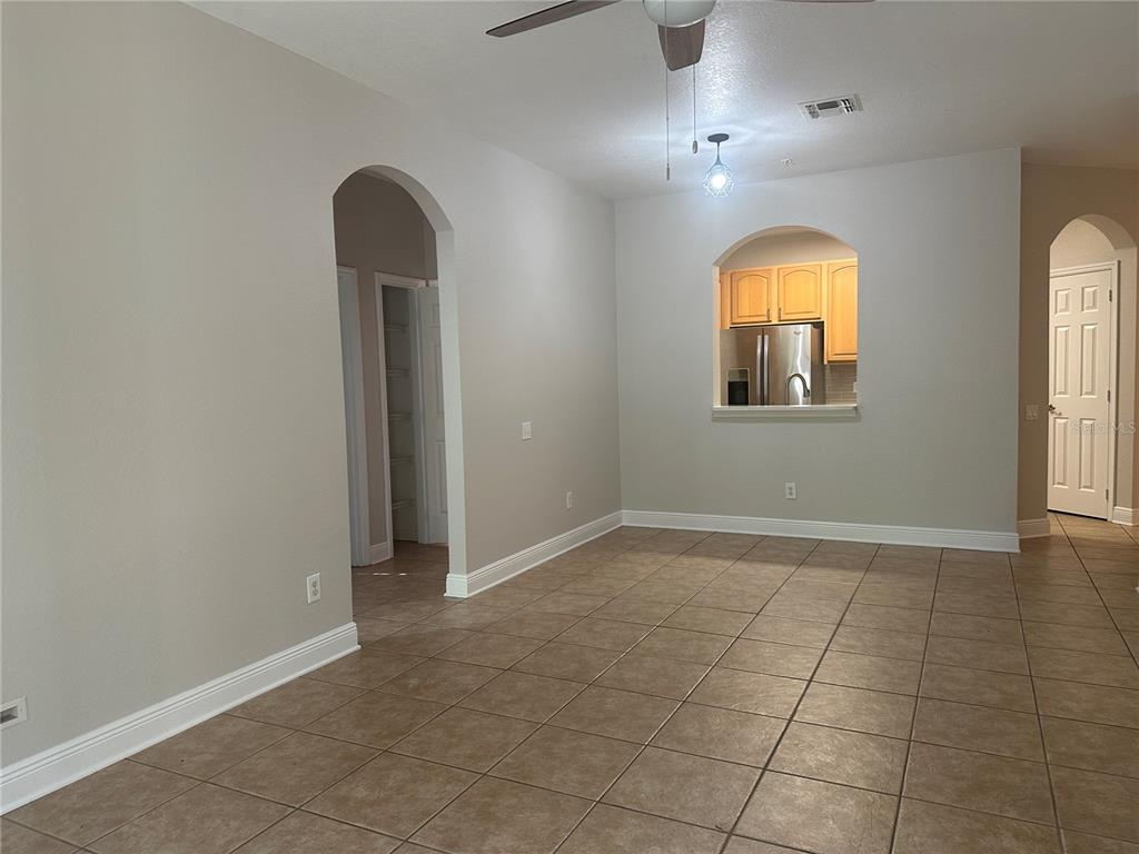 An interior view of a room with tile flooring, an arched doorway, and a kitchen pass-through — 588 BRANTLEY TERRACE WAY UNIT 109, ALTAMONTE SPRINGS, FL