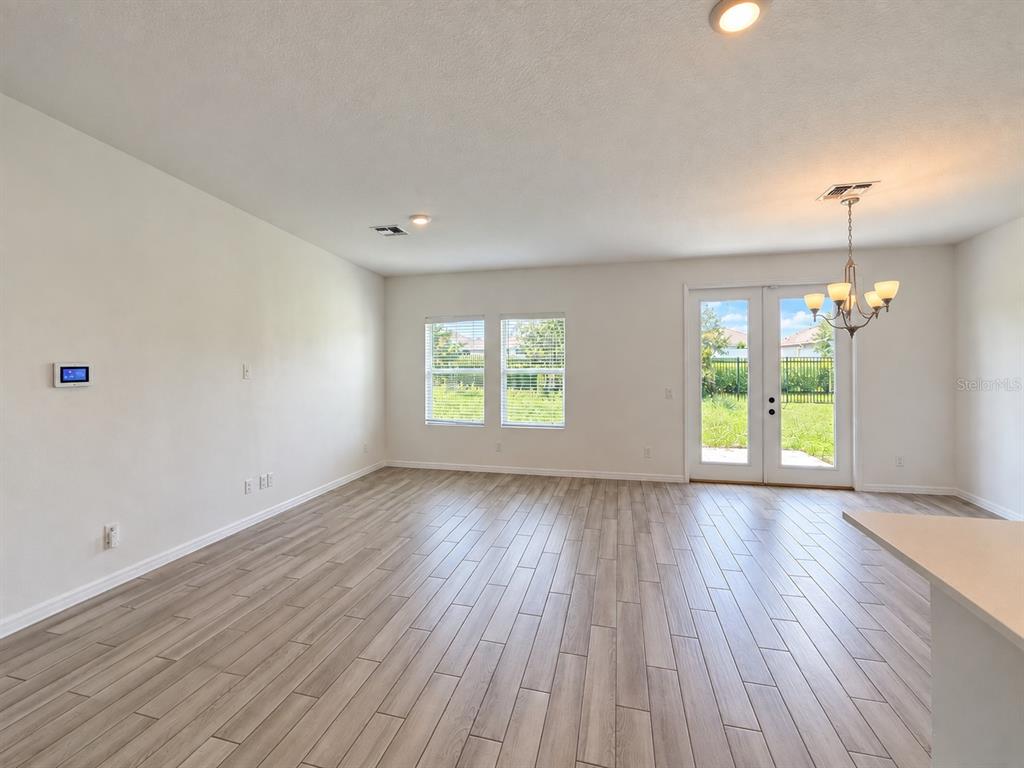 A living area features wood-look tile flooring, a tropical floral accent wall, and glass patio doors — 2074 DERWENT DRIVE, DAVENPORT, FL