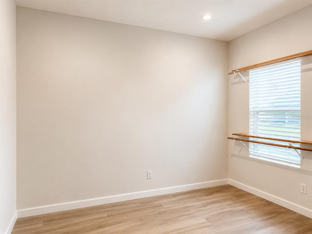 An empty room with light-colored walls, wood-look flooring, and a window with ballet barres — 2074 DERWENT DRIVE, DAVENPORT, FL