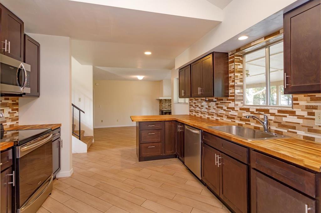 A kitchen features dark wood cabinets, butcher block countertops, and a tiled backsplash — 7925 SNOWBERRY CIRCLE, ORLANDO, FL