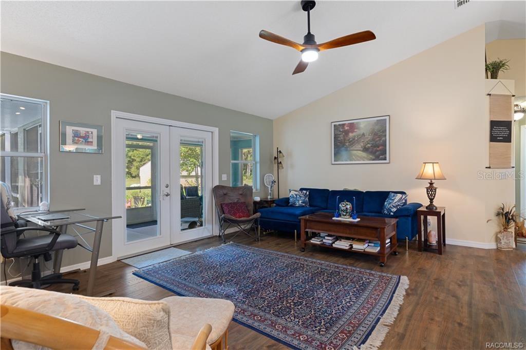 A living room with a blue sectional sofa, wood flooring, and a ceiling fan — 9690 N ALDER AVENUE, CRYSTAL RIVER, FL