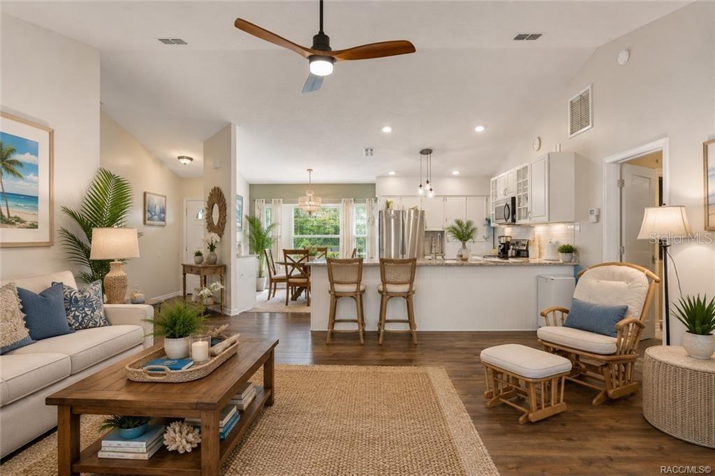 An open-concept living room and kitchen feature wood flooring, a ceiling fan, and coastal decor — 9690 N ALDER AVENUE, CRYSTAL RIVER, FL