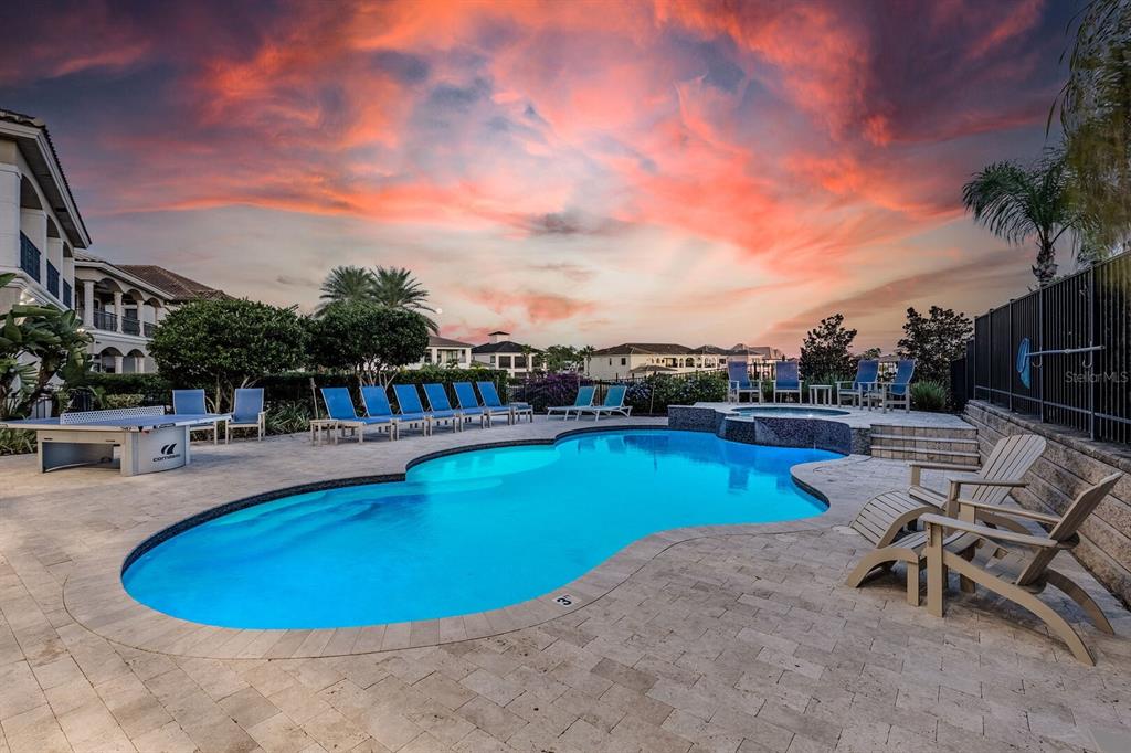 A swimming pool with lounge chairs and a ping pong table at sunset — 445 MUIRFIELD LOOP, REUNION, FL