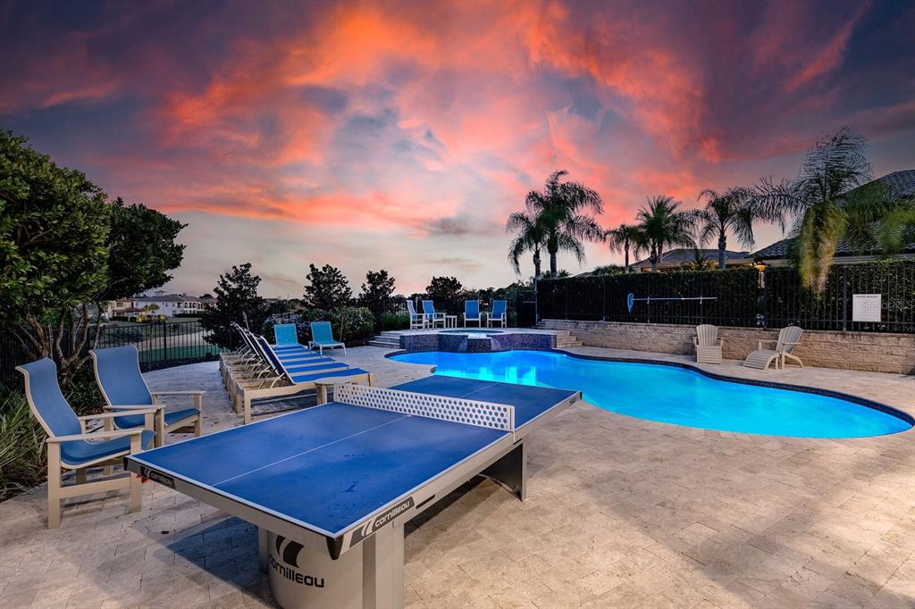 A blue ping pong table sits on a patio next to a swimming pool at sunset — 445 MUIRFIELD LOOP, REUNION, FL