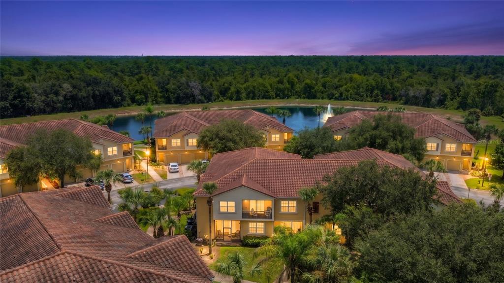 An aerial view of a multi-story apartment complex with tile roofs overlooking a small lake — 2742 OAKWATER DRIVE UNIT 104, KISSIMMEE, FL