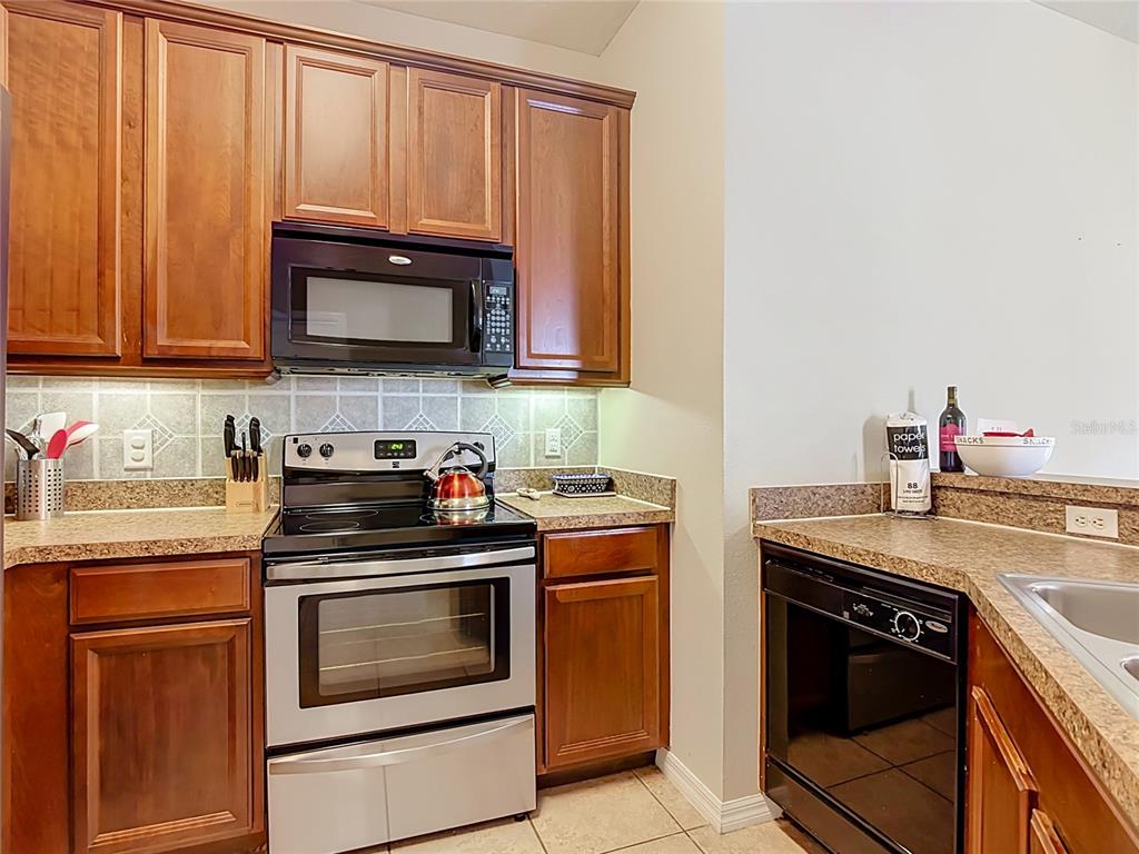 A kitchen features wood cabinets, stainless steel appliances, and tan speckled countertops — 2742 OAKWATER DRIVE UNIT 104, KISSIMMEE, FL