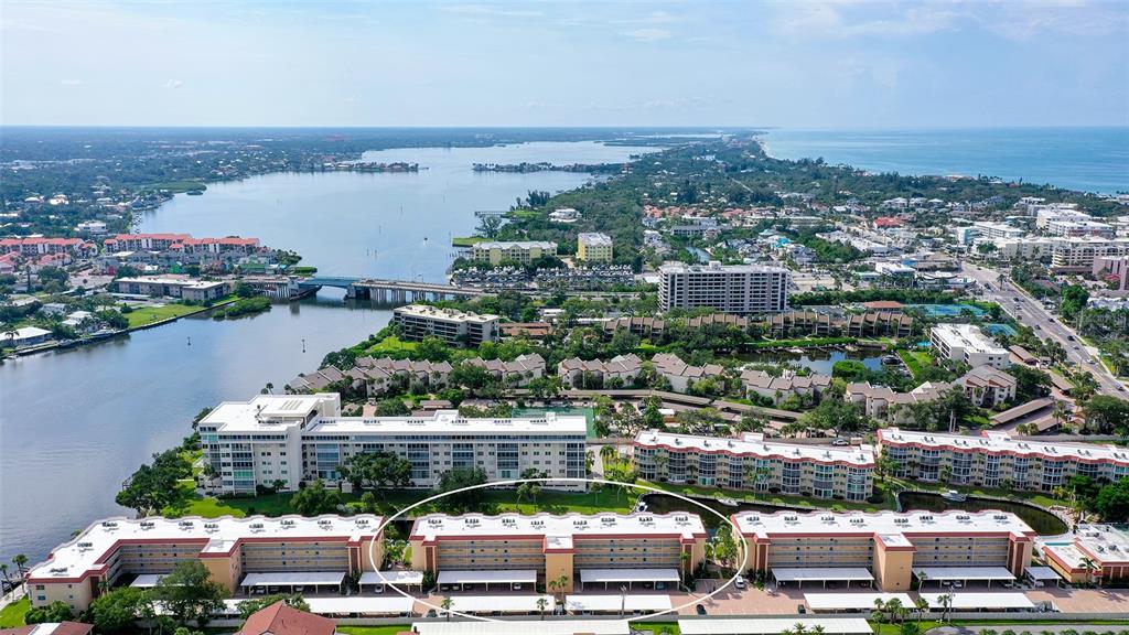 An aerial view shows a multi-story apartment complex with covered parking near a waterway — 1300 N PORTOFINO DRIVE UNIT 103, SARASOTA, FL