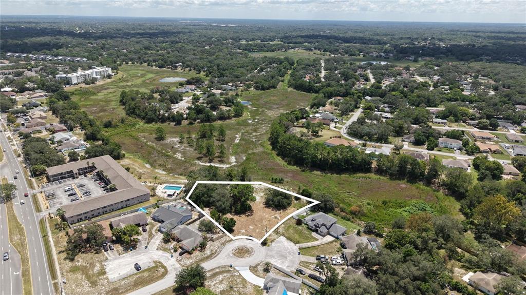 An aerial view shows a vacant, irregularly shaped residential lot surrounded by suburban homes — 1170 PORT COURT, SPRING HILL, FL