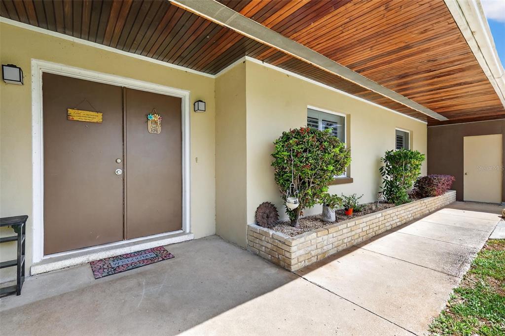 A covered concrete porch features double brown doors, a brick planter, and wood-paneled ceiling — 17923 FLORIDA STREET, UMATILLA, FL