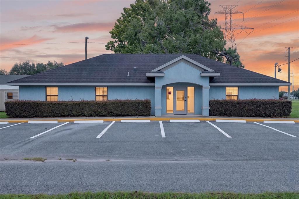 A single-story blue commercial building with a parking lot and hedges in front — 7133 SE MARICAMP ROAD, OCALA, FL