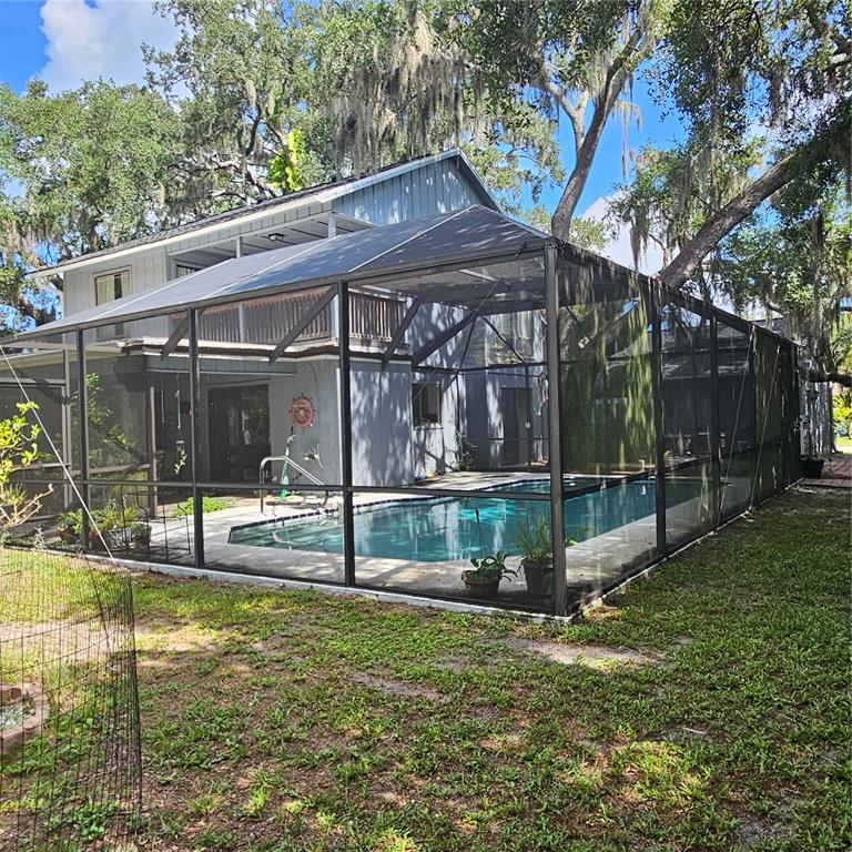 A backyard swimming pool is enclosed by a large screened-in lanai attached to a house — 4841 HAWKSHEAD PARK, SARASOTA, FL