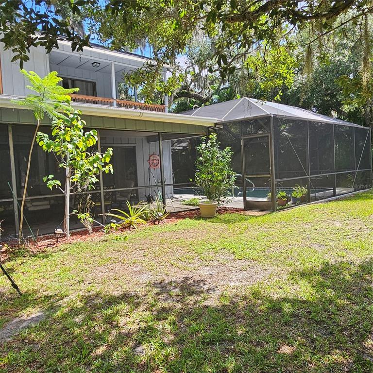 A backyard features a screened-in patio and pool enclosure attached to a two-story house — 4841 HAWKSHEAD PARK, SARASOTA, FL