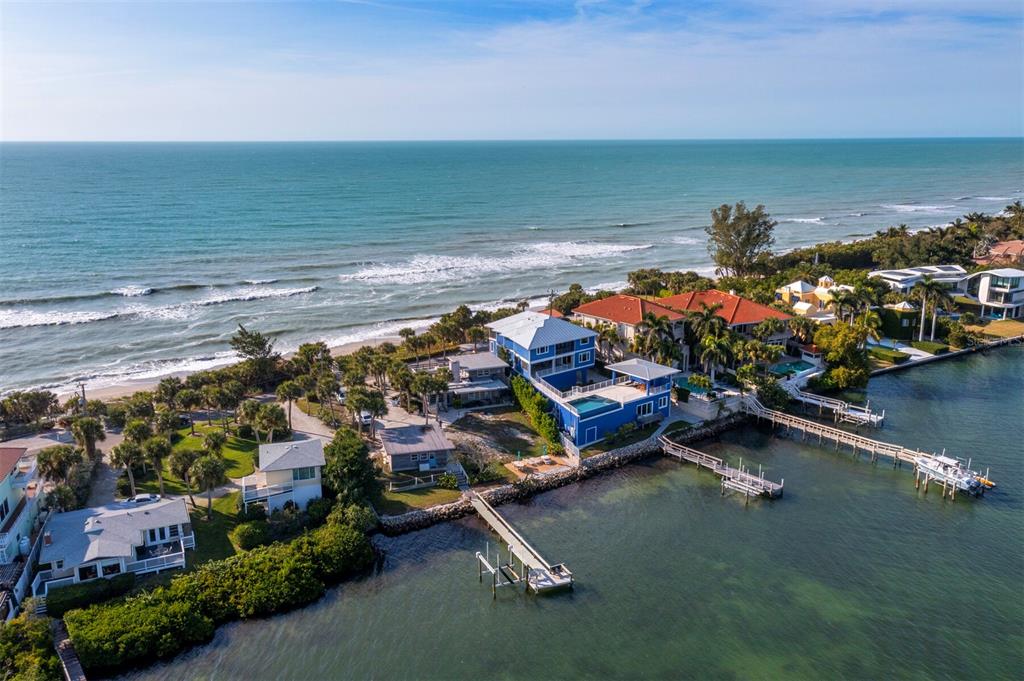 An aerial view of a blue multi-story house situated between the ocean and a bay — 1620 CASEY KEY ROAD, NOKOMIS, FL