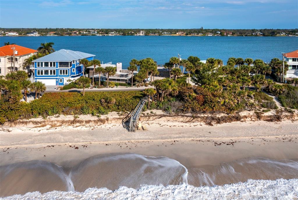 An aerial view shows a beach with a wooden staircase leading to a coastal home — 1620 CASEY KEY ROAD, NOKOMIS, FL