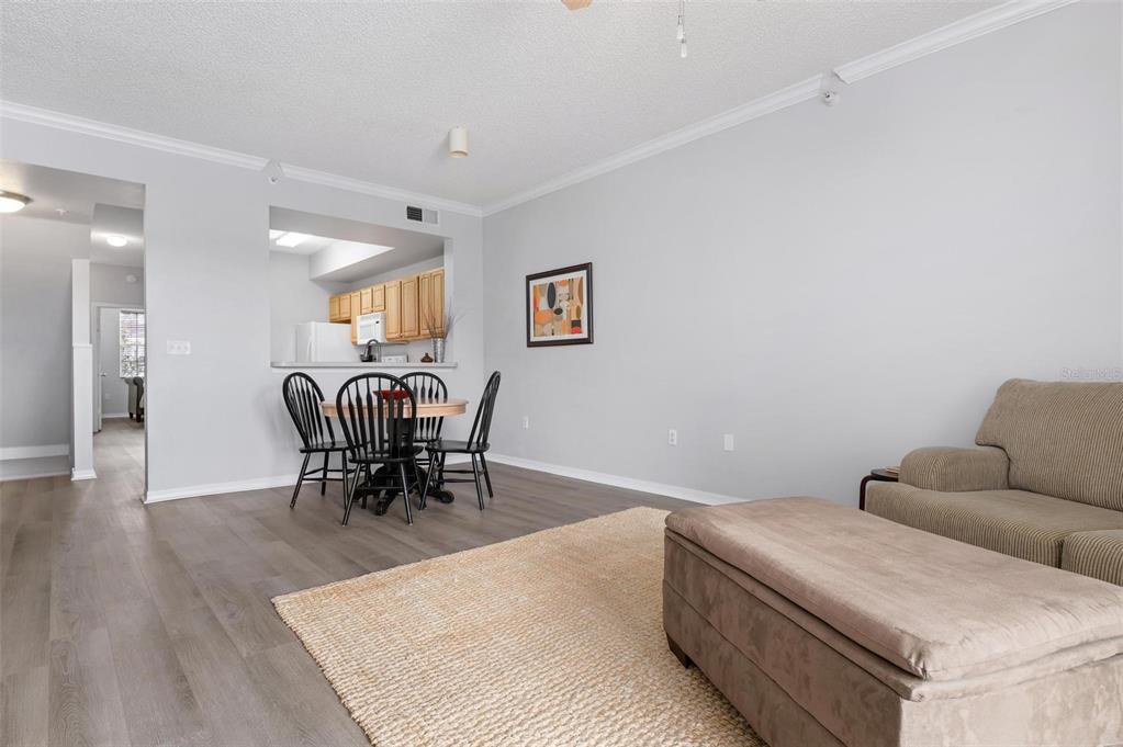 A living room with wood-look flooring, a dining area, and an open kitchen pass-through — 5681 BENTGRASS DRIVE UNIT 204, SARASOTA, FL
